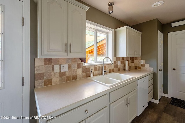 kitchen featuring white dishwasher, decorative backsplash, white cabinets, and sink