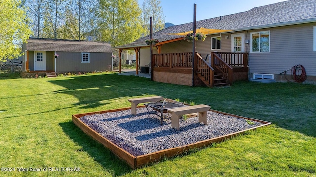 rear view of house featuring a yard, a fire pit, an outdoor structure, and a wooden deck