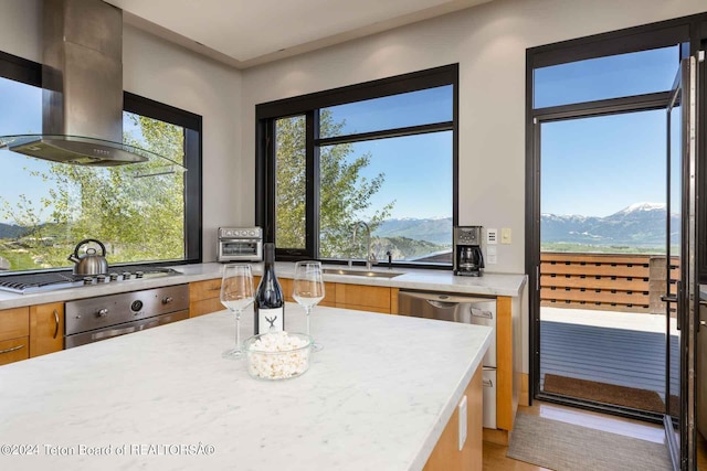 kitchen with light stone countertops, appliances with stainless steel finishes, wall chimney exhaust hood, sink, and a mountain view