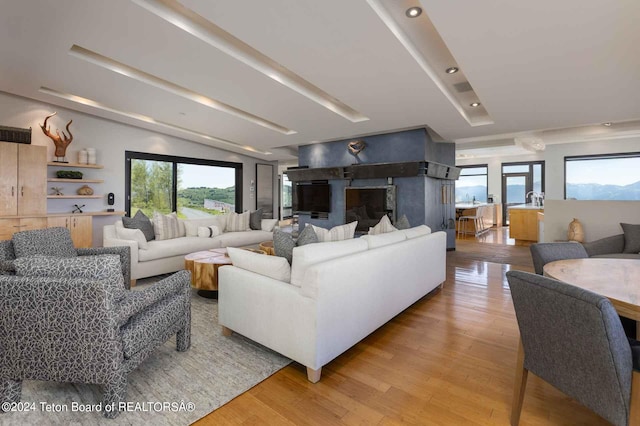 living room featuring a large fireplace, light hardwood / wood-style floors, a wealth of natural light, and lofted ceiling