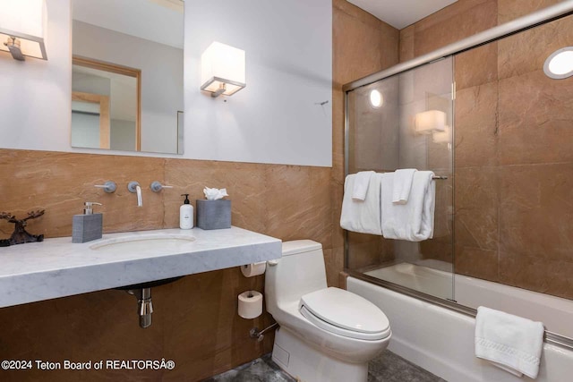 full bathroom featuring sink, tasteful backsplash, toilet, shower / bath combination with glass door, and tile walls