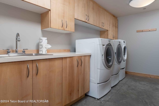 clothes washing area with cabinets, washing machine and dryer, and sink