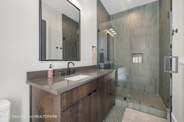 bathroom featuring vanity, toilet, and tiled shower