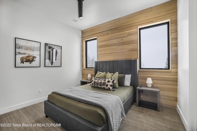 carpeted bedroom featuring multiple windows and wooden walls