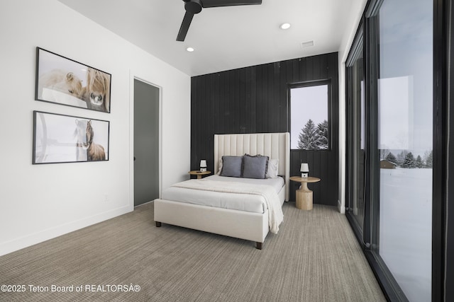 carpeted bedroom featuring ceiling fan and wooden walls