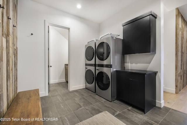 clothes washing area with cabinets and stacked washer and clothes dryer