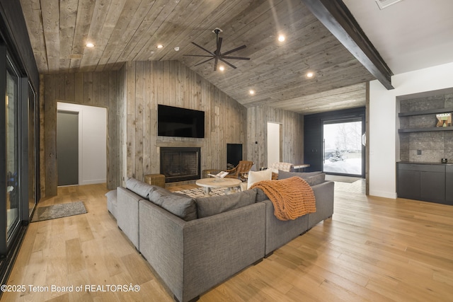 living room with a stone fireplace, ceiling fan, vaulted ceiling, and light wood-type flooring