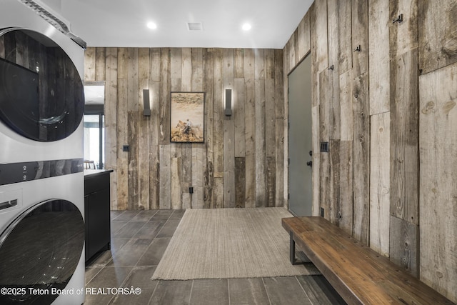 laundry room featuring stacked washer / dryer and wooden walls