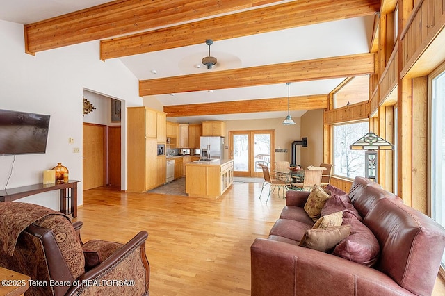 living area with light wood-style flooring and vaulted ceiling with beams