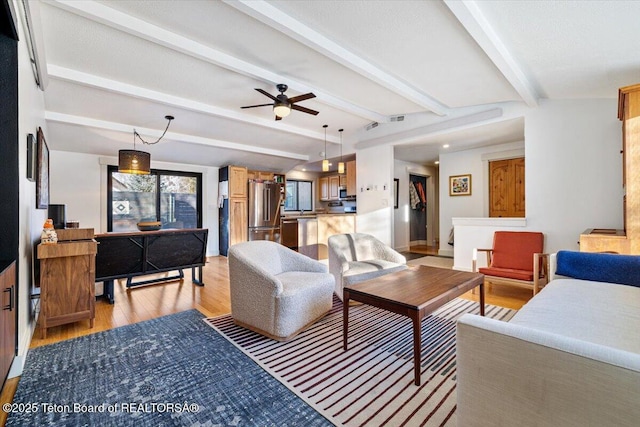 living room with ceiling fan, light hardwood / wood-style flooring, and beamed ceiling