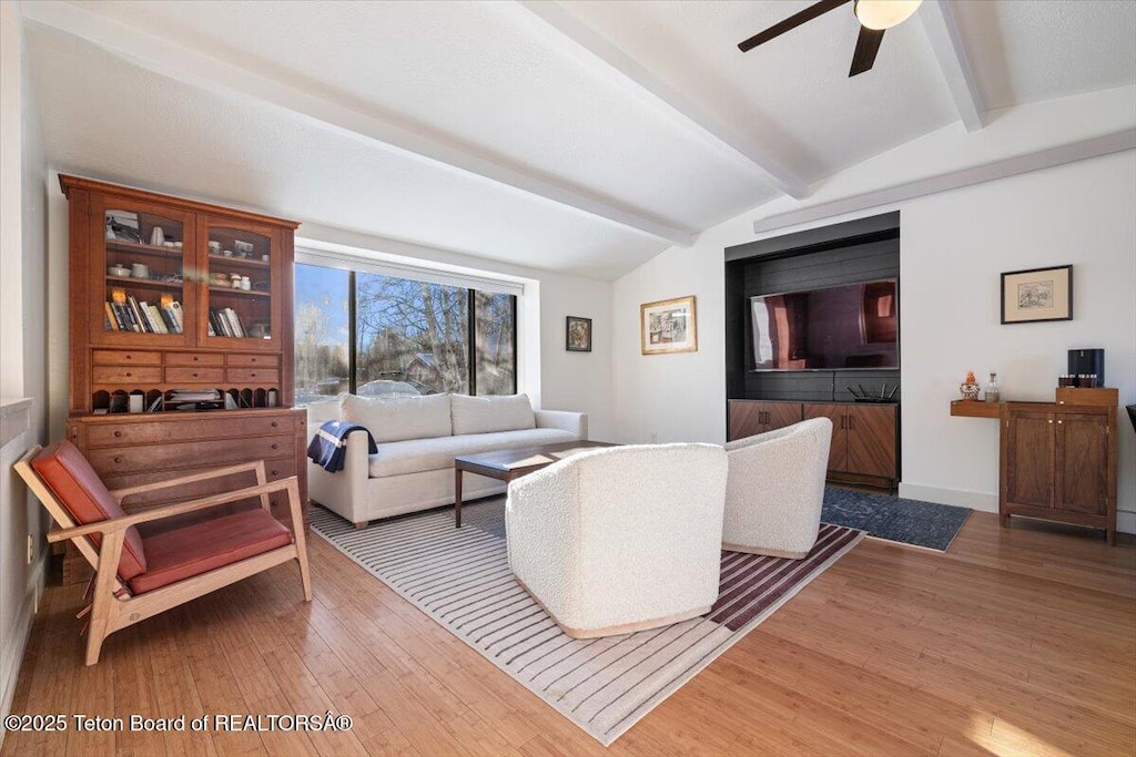 living room with hardwood / wood-style flooring, ceiling fan, and vaulted ceiling with beams