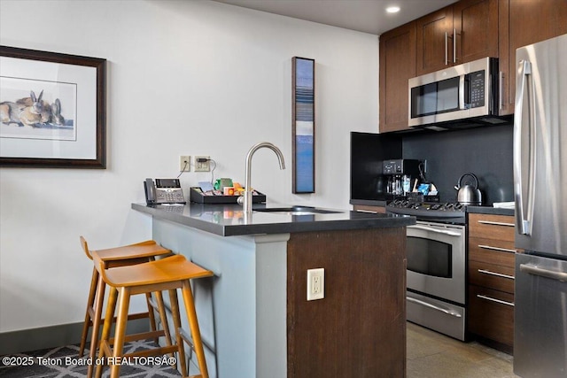 kitchen featuring appliances with stainless steel finishes, sink, a kitchen breakfast bar, backsplash, and kitchen peninsula