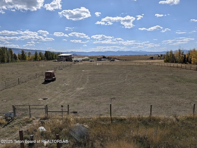 view of yard featuring a mountain view, a rural view, and fence