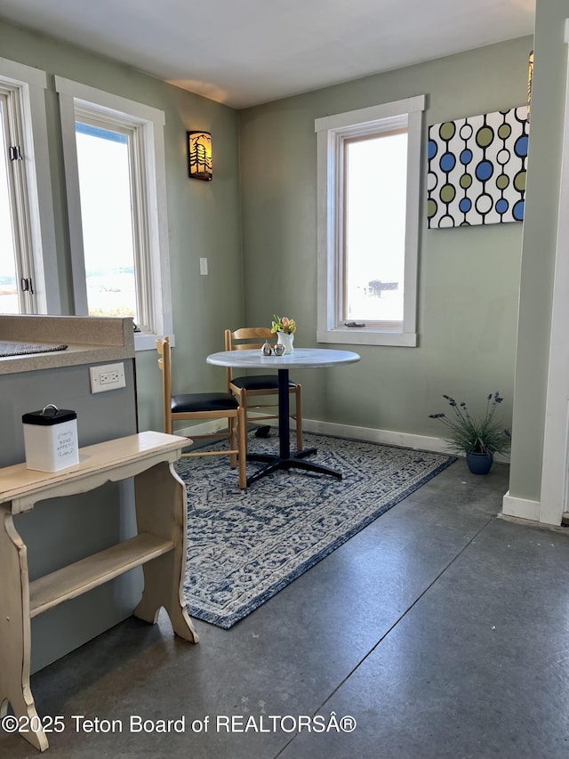 dining space featuring a wealth of natural light, baseboards, and concrete floors