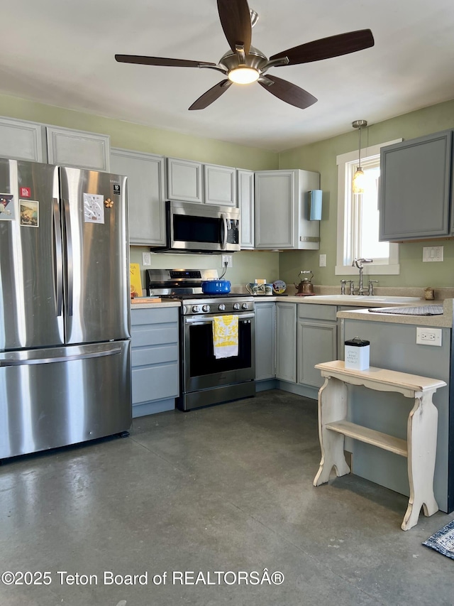 kitchen featuring gray cabinetry, light countertops, hanging light fixtures, stainless steel appliances, and a sink