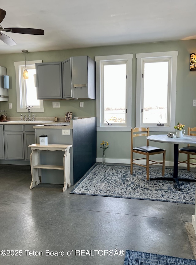 kitchen featuring baseboards, gray cabinets, a sink, light countertops, and decorative light fixtures