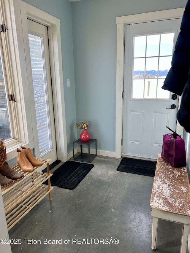 doorway to outside featuring baseboards and concrete floors