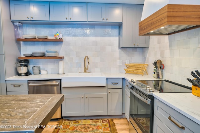 kitchen featuring island range hood, appliances with stainless steel finishes, tasteful backsplash, light stone counters, and sink