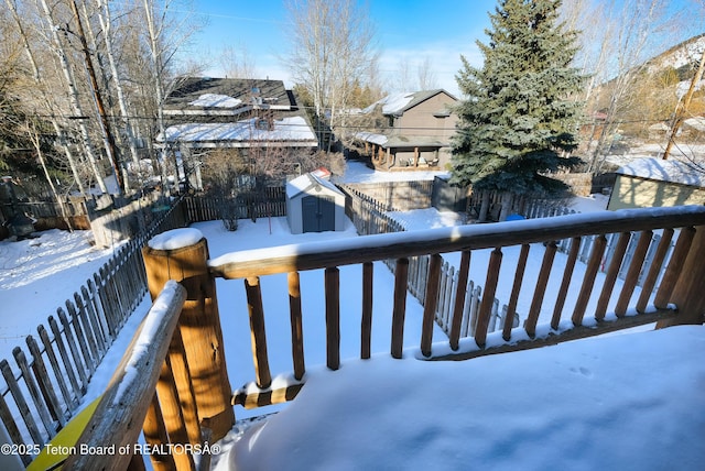 snow covered deck featuring a storage shed