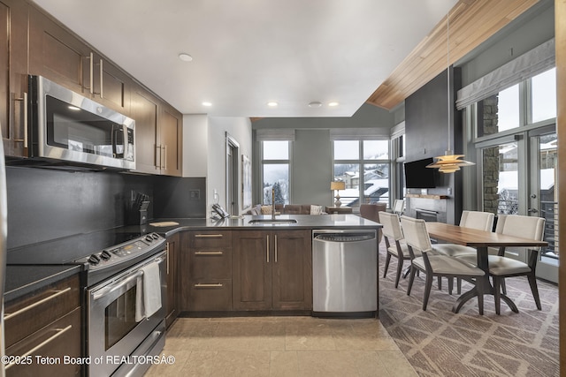 kitchen featuring appliances with stainless steel finishes, tasteful backsplash, sink, kitchen peninsula, and dark brown cabinets