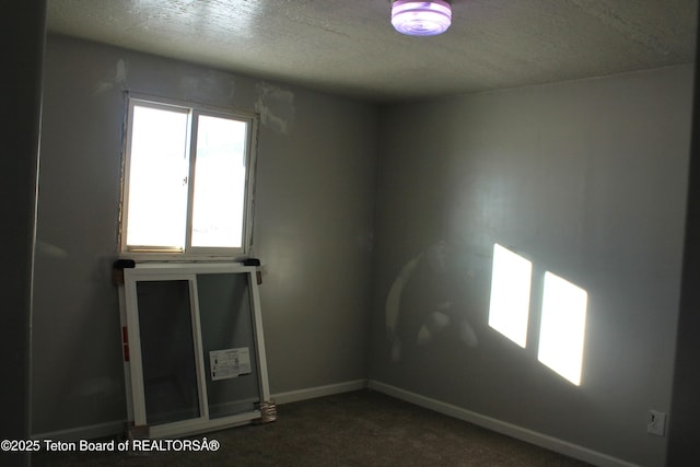 carpeted empty room with a textured ceiling