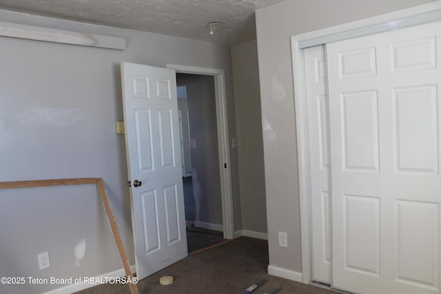 unfurnished bedroom with dark carpet, a closet, and a textured ceiling