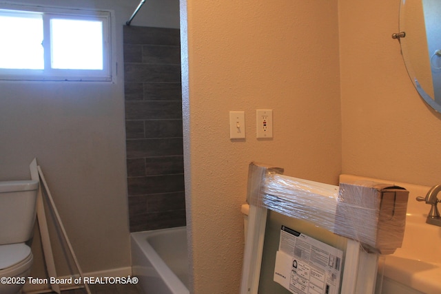 bathroom featuring toilet and tiled shower / bath combo