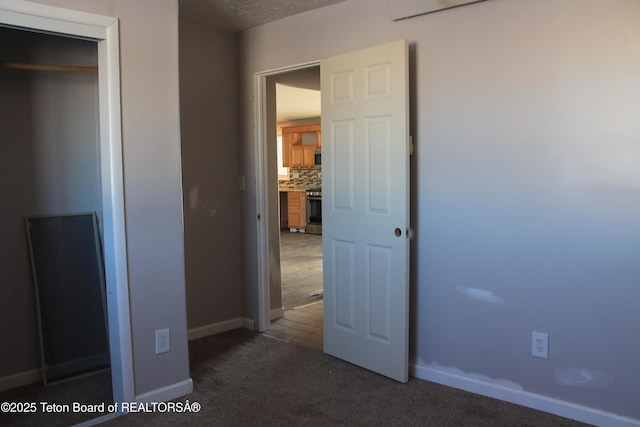 unfurnished bedroom with dark colored carpet and a closet