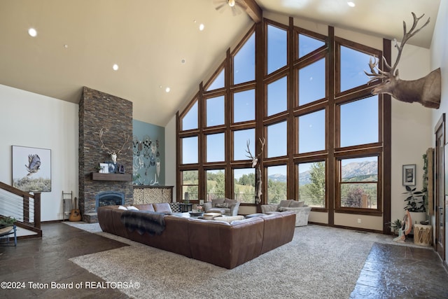 living room featuring ceiling fan, beamed ceiling, a fireplace, and high vaulted ceiling