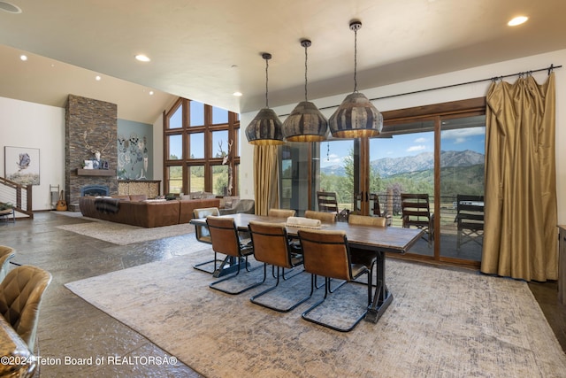 dining room featuring a mountain view, a stone fireplace, and high vaulted ceiling