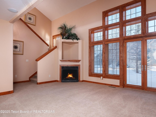 unfurnished living room featuring light carpet, plenty of natural light, and high vaulted ceiling