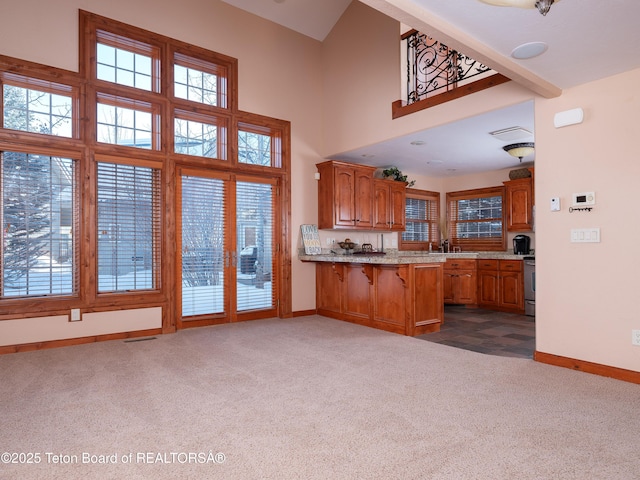 kitchen featuring sink, dark carpet, stainless steel stove, and kitchen peninsula