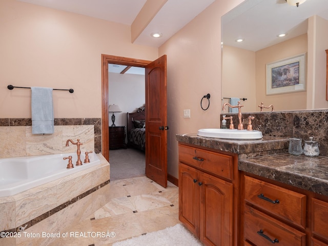 bathroom with tiled tub and vanity