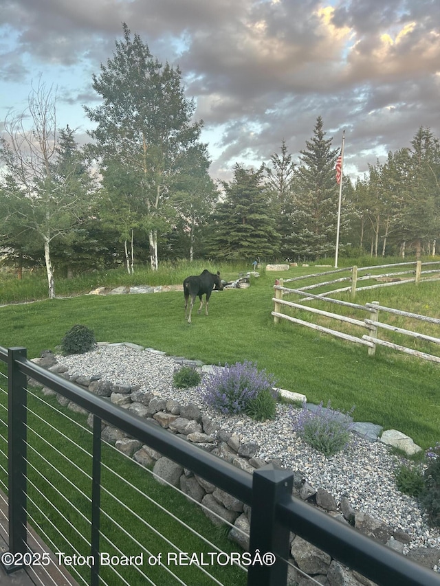 view of property's community with fence, a lawn, and a rural view