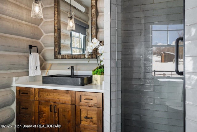 bathroom featuring rustic walls, tiled shower, and vanity