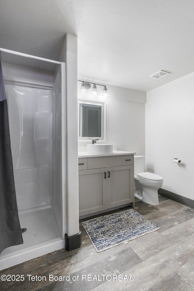 full bath with a stall shower, visible vents, toilet, wood finished floors, and vanity