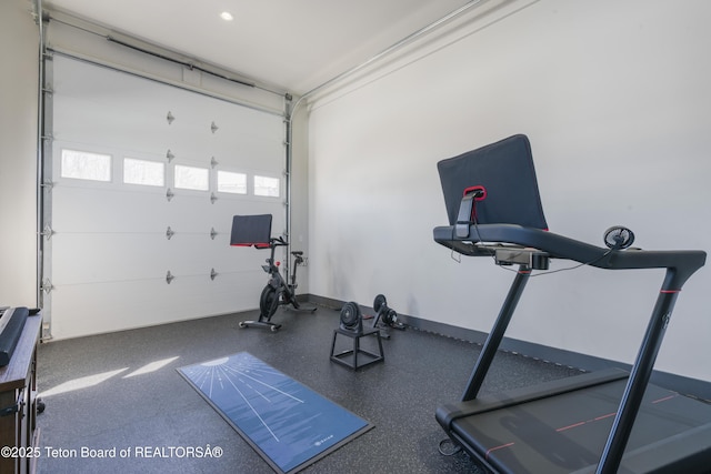 exercise area with a garage and baseboards