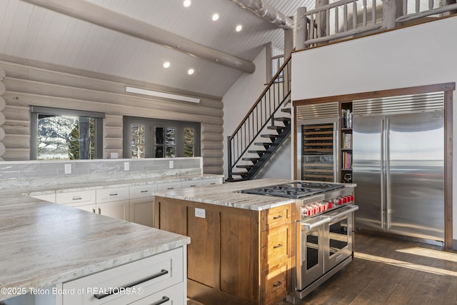 kitchen with high vaulted ceiling, high quality appliances, log walls, beam ceiling, and dark wood-style floors