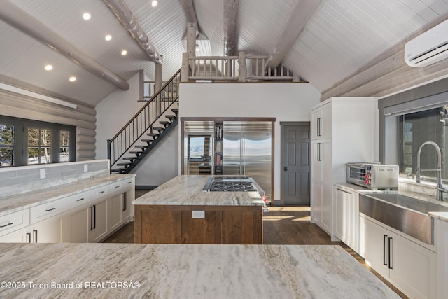 kitchen featuring a wall unit AC, rustic walls, a sink, light stone countertops, and built in refrigerator