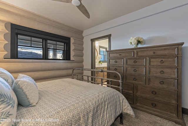 bedroom featuring carpet, log walls, and ceiling fan