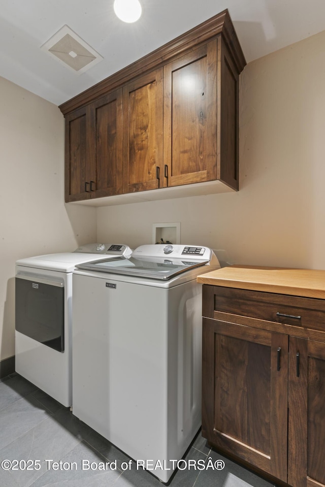 laundry area with light tile patterned floors, cabinet space, and separate washer and dryer