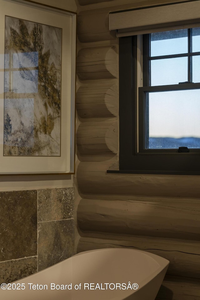 bathroom with a soaking tub and log walls