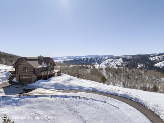 yard covered in snow featuring a mountain view and an attached garage