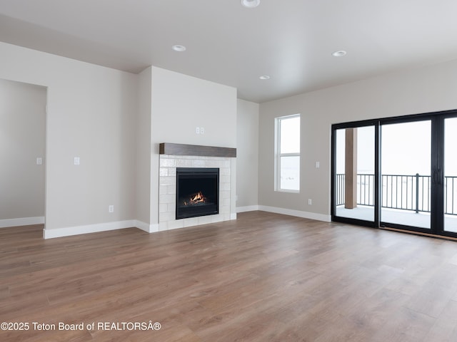 unfurnished living room featuring light hardwood / wood-style flooring and a tiled fireplace