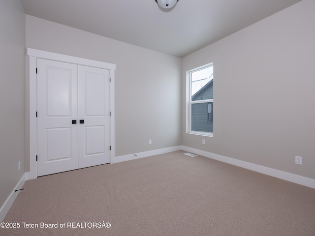 unfurnished bedroom featuring light colored carpet and a closet