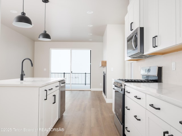 kitchen with decorative light fixtures, appliances with stainless steel finishes, light stone counters, and white cabinetry