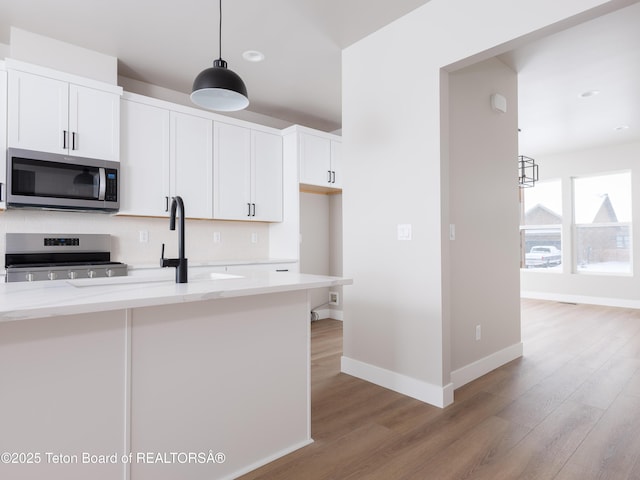 kitchen with light stone countertops, backsplash, white cabinets, and stainless steel appliances