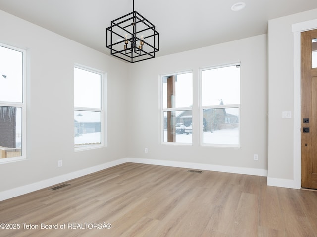 interior space featuring a wealth of natural light, light hardwood / wood-style flooring, and an inviting chandelier