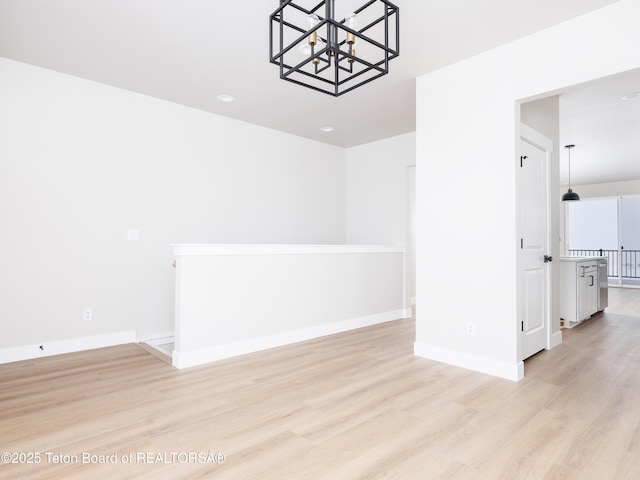 spare room with light wood-type flooring and a notable chandelier