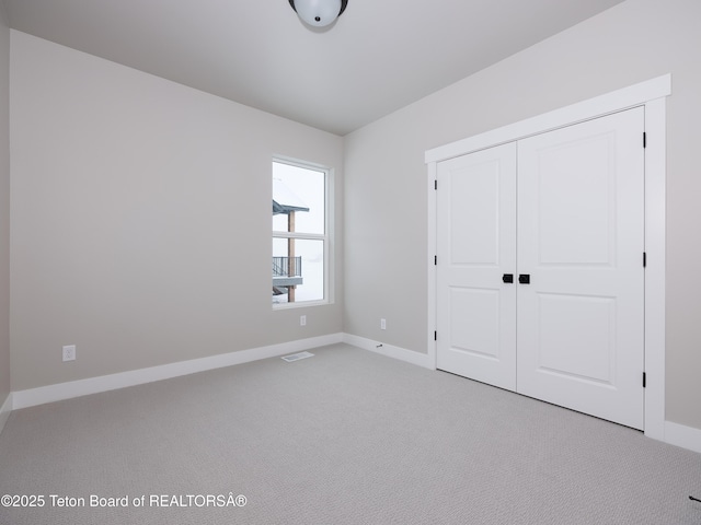 unfurnished bedroom featuring light colored carpet and a closet